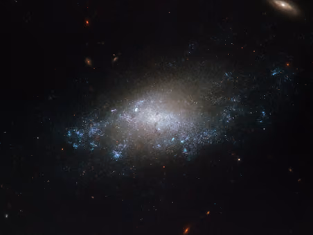 Faint spiral galaxy NGC 3274, a bluish haze of stars against dark space