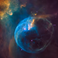 Bubble Nebula: a blue bubble of gas blown by a massive star, among clouds of orange and teal