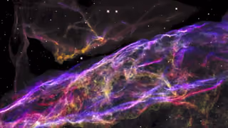 Tangled filaments of pink, violet and yellow gas in the Veil Nebula, the remains of an exploded star