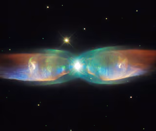 Twin Jet Nebula: two shimmering lobes of blue and green gas spreading from a bright central star