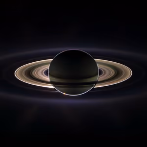 Saturn backlit by the Sun, its rings glowing around the dark planet