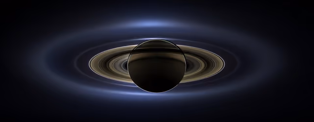 Saturn and its rings backlit by the Sun, with Earth a tiny dot far below the rings