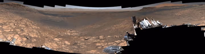 Wide panorama of rocky Martian ground and distant hills under a hazy sky