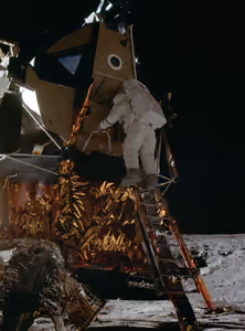 Alan Bean climbing down the ladder of the lunar module onto the Moon, in shadow
