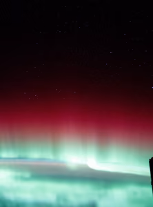 Red and green aurora borealis shimmering above Canada, seen from orbit