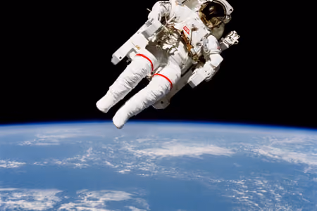 Bruce McCandless flying untethered with a jetpack above Earth